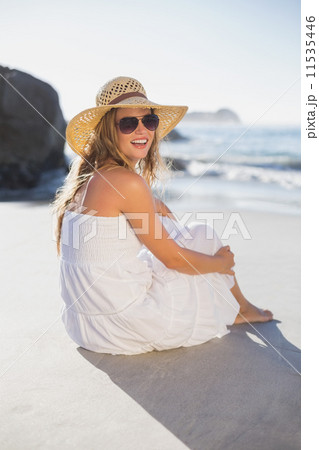 Beautiful smiling blonde in sundress sitting on the beach 11535446