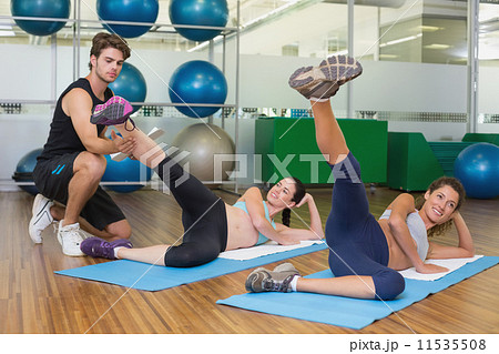 Fit women working out together in studio with trainer 11535508