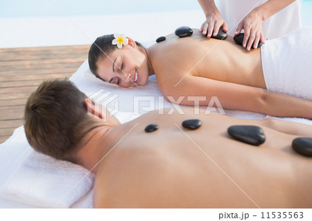 Attractive couple enjoying hot stone massage poolside 11535563