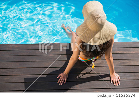 Beautiful brunette in bikini sitting by the pool paddling 11535574