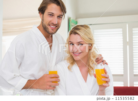 Cute couple in bathrobes smiling at camera together having break 11535582