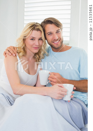 Smiling casual couple sitting on couch having coffee Smiling casual couple sitting on couch having coffee 11535661