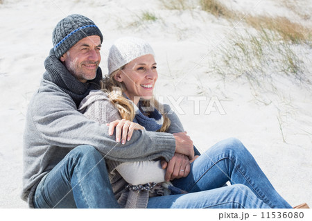 Attractive couple smiling on the beach in warm clothing Attractive couple smiling on the beach in warm clothing 11536080