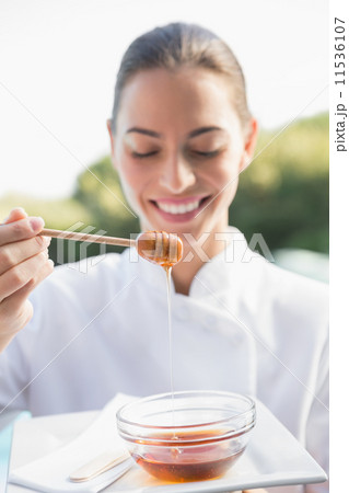 Smiling beauty therapist holding plate with honey 11536107