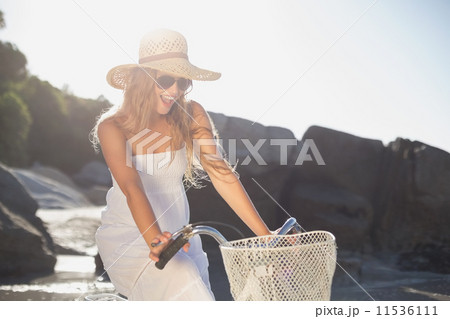 Beautiful smiling blonde in sundress on bike at the beach 11536111