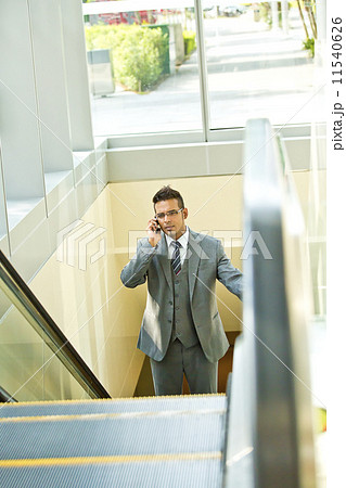 Young businessman talking on smart phone walking up escalator Young businessman talking on smart phone walking up escalator 11540626