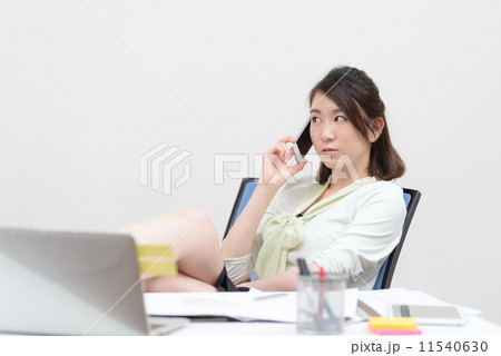 机に足をのせて電話する女性 11540630