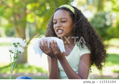 Young girl sitting by flower and sneezing in the park Young girl sitting by flower and sneezing in the park 11553104