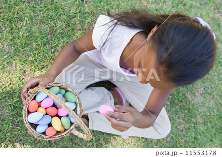Little girl sitting on grass counting easter eggs Little girl sitting on grass counting easter eggs 11553178