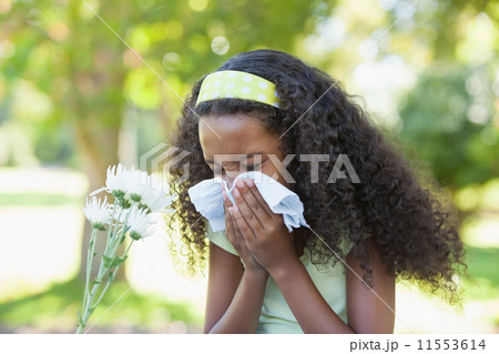 Young girl sitting by flower and blowing her nose in the park Young girl sitting by flower and blowing her nose in the park 11553614