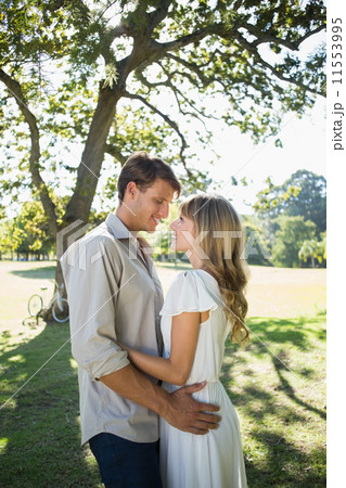 Smiling couple standing and embracing in park Smiling couple standing and embracing in park 11553995