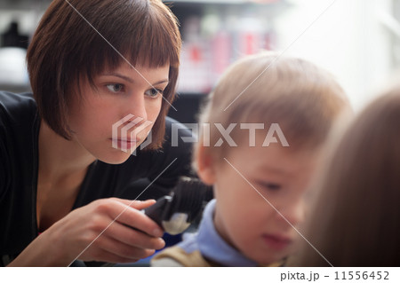 Hairstylist cutting a young boys hair 11556452