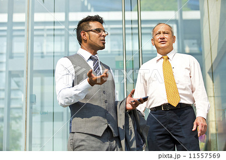 Senior businessman and young businessman outside glass building Senior businessman and young businessman outside glass building 11557569