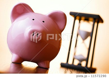 Pink piggy bank with a vintage hourglass behind Pink piggy bank with a vintage hourglass behind 11572290