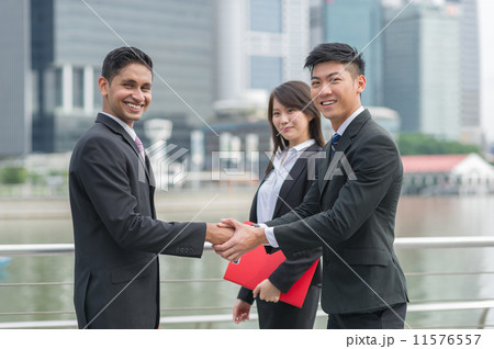 A successful Chinese businessman with his female assistant hand shake with his Indian partner A successful Chinese businessman with his female assistant hand shake with his Indian partner 11576557