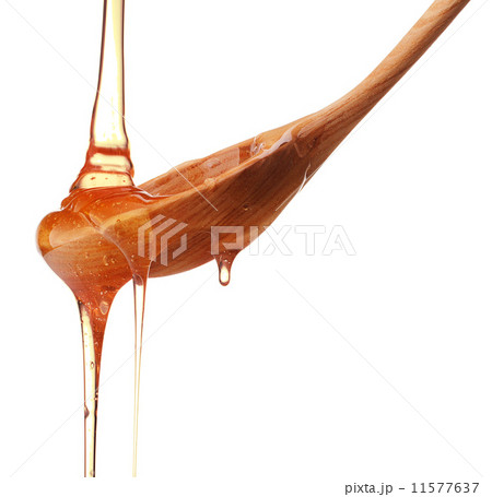 Honey dripping from a wooden honey dipper isolated on white back Honey dripping from a wooden honey dipper isolated on white back 11577637