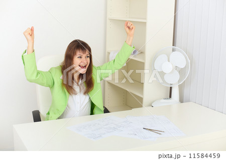 Exulting young woman sits at a table Exulting young woman sits at a table 11584459