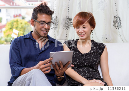 Asian mixed couple enjoying moment together, using digital tablet Asian mixed couple enjoying moment together, using digital tablet 11586211