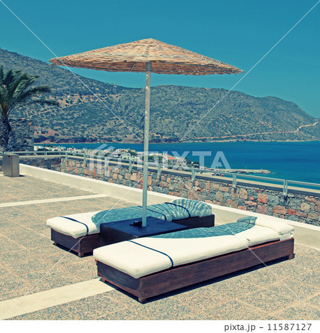 Sun beds and umbrellas on terrace in summer resort 11587127