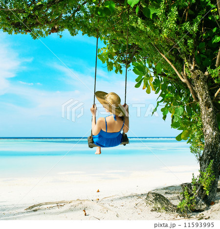 Woman in blue dress swinging at beach 11593995