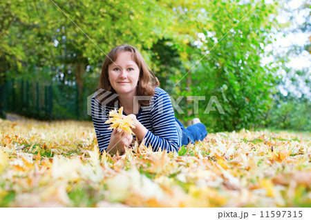 Girl lying on the ground covered with fall leaves 11597315