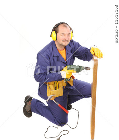 Worker in ear muffs with drill and board. 11612163