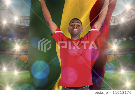 Composite image of excited handsome football fan cheering holdin Composite image of excited handsome football fan cheering holdin 11618176