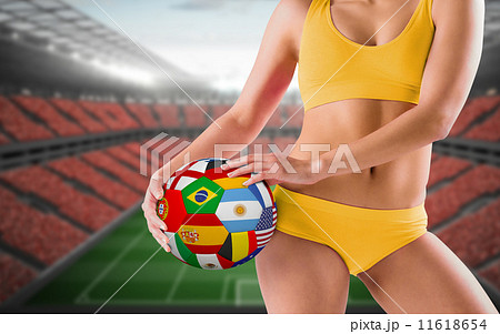 Composite image of fit girl in yellow bikini holding flag football 11618654