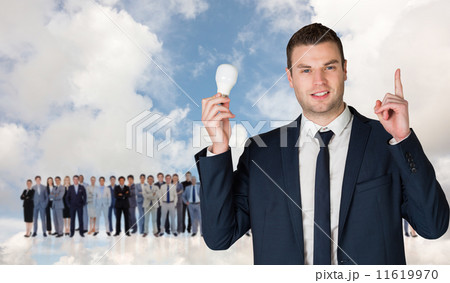 Composite image of businessman holding light bulb and pointing 11619970