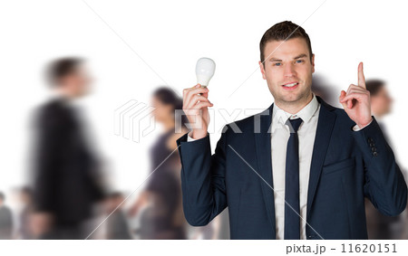 Composite image of businessman holding light bulb and pointing 11620151