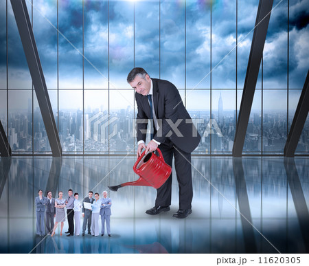 Composite image of mature businessman watering tiny business tea 11620305