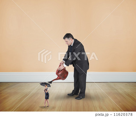 Composite image of mature businessman watering tiny businesswoma Composite image of mature businessman watering tiny businesswoma 11620378