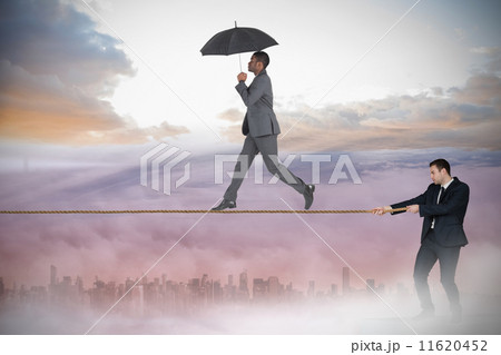 Young businessman pulling a tightrope for business man Young businessman pulling a tightrope for business man 11620452