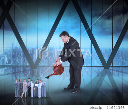 Composite image of mature businessman watering tiny business tea 11621363