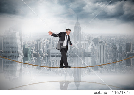 Composite image of mature businessman doing a balancing act on t Composite image of mature businessman doing a balancing act on t 11621375