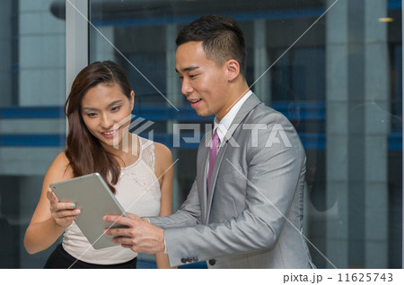 Two young and dynamic asian co-workers are having a discussion or sharing information on the tablet 11625743