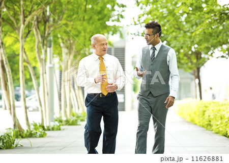 Senior businessman and young businessman having a discussion while walking 11626881