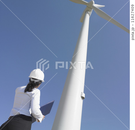 Female engineer examining wind turbine Female engineer examining wind turbine 11627409