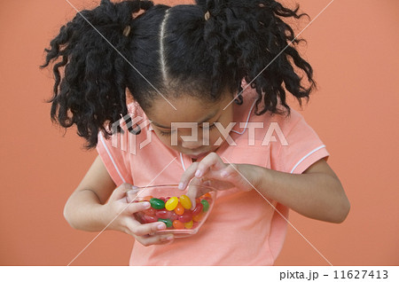 Asian girl with ponytails looking in bowl of candy 11627413