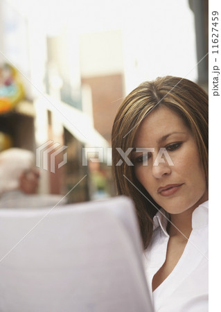 Hispanic businesswoman reading paperwork outdoors 11627459