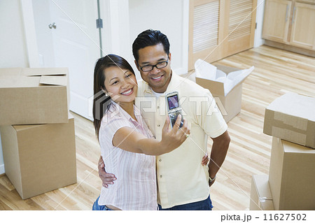 Asian couple taking own photograph in new house 11627502