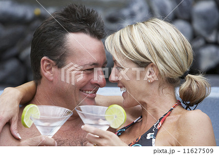 Couple drinking cocktails in hot tub 11627509