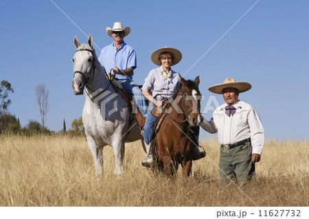 Hispanic man leading couple on horses 11627732