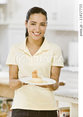 Hispanic woman holding plate of dessert 11627735