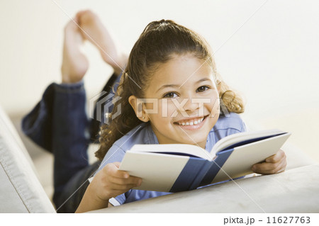 Portrait of African girl holding book on sofa 11627763
