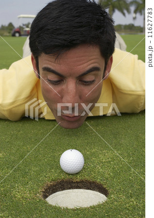 Hispanic man blowing on golf ball Hispanic man blowing on golf ball 11627783