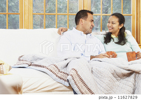 Couple sitting on the couch under a blanket together 11627829