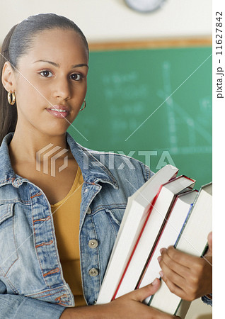 Female Dominican teenager holding her books in classroom 11627842