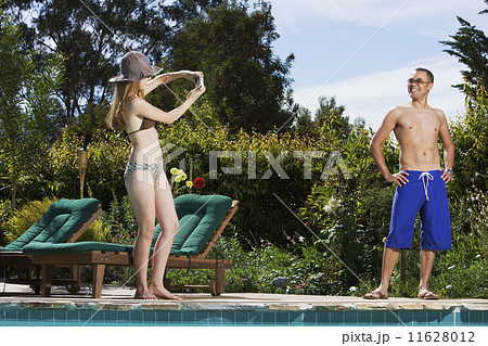 Hispanic woman taking photograph of boyfriend 11628012