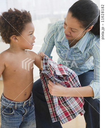 Mixed race mother helping son to dress Mixed race mother helping son to dress 11628182